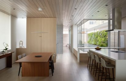 Open-plan kitchen and dining room with large windows looking onto an outdoor swimming pool