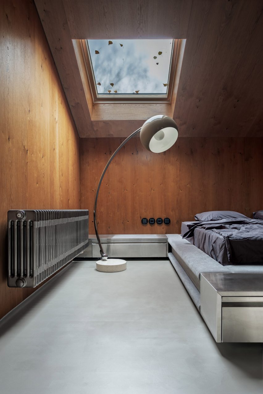 Bed in wood-panelled bedroom with retro lighting