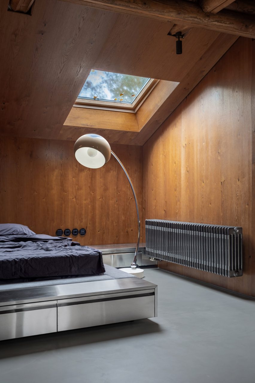 Bed in wood-panelled bedroom with retro lighting