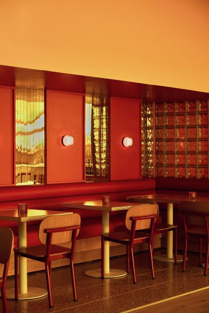 Seating area with red leather banquette and cafe tables