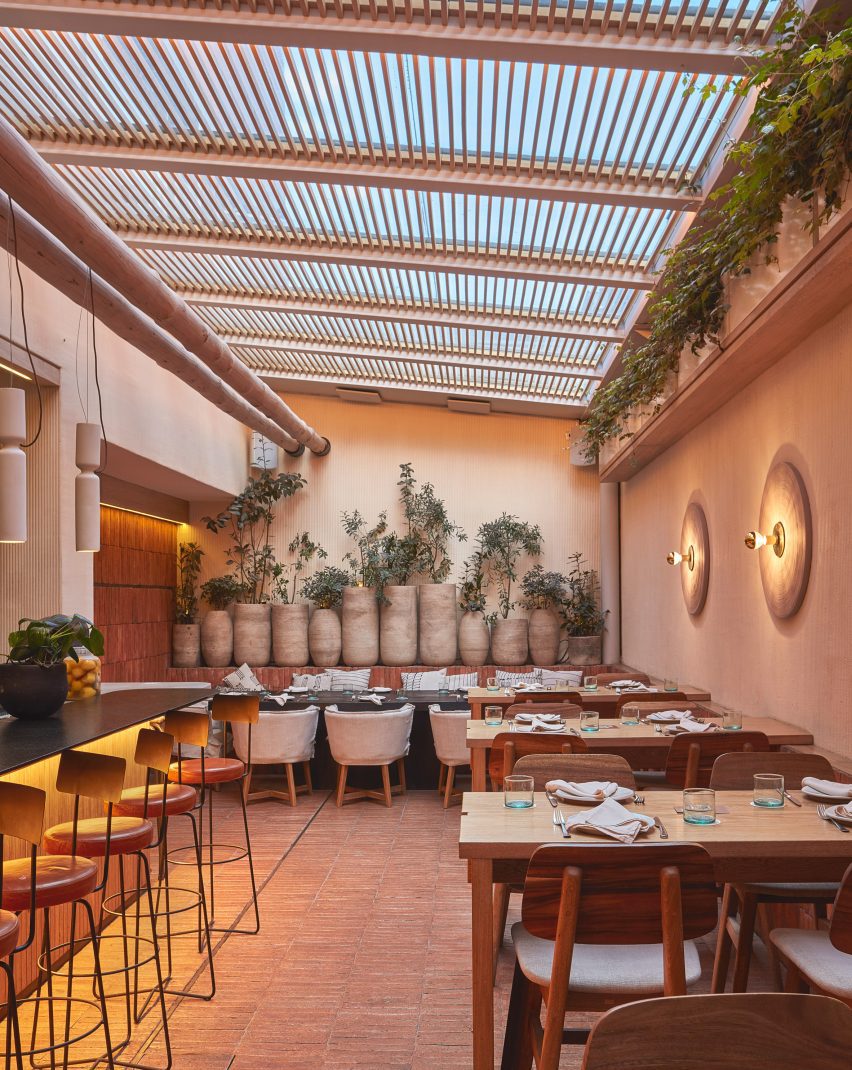 An outdoor seating area with wooden chairs and plants in large pots