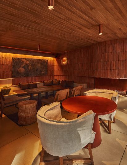 Fabric chairs and a red table in front of a curving wall of brick