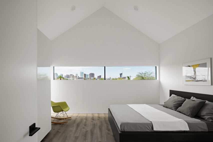 Bedroom with a pitched roof, white walls and narrow window