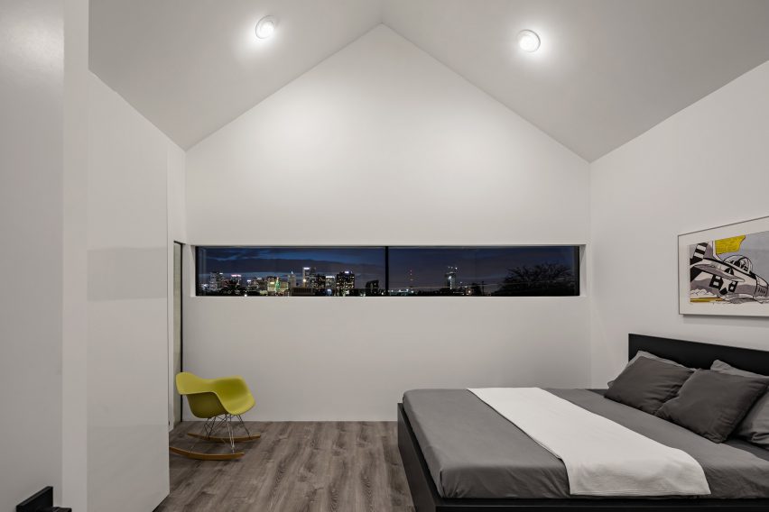 Bedroom with a pitched roof, white walls and narrow window