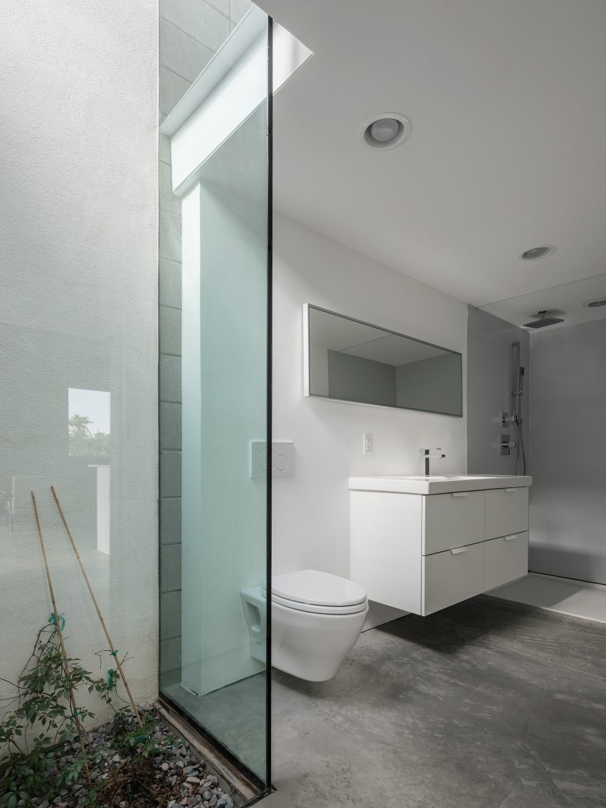 Bathroom with concrete flors, white walls and glass shower door
