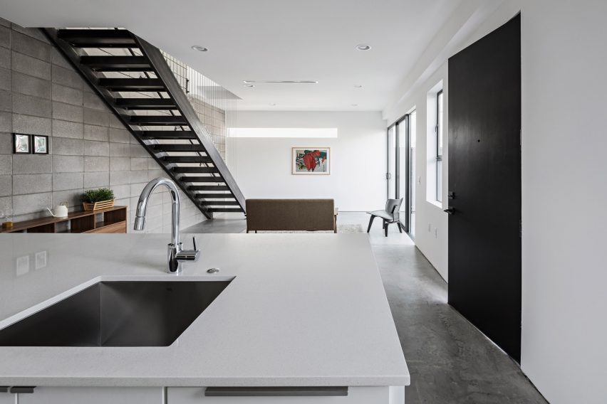 Open-plan kitchen and dining room with a white island and steel staircase