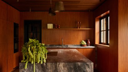 Kitchen interior by DAB Studio with timber walls and a marble kitchen island