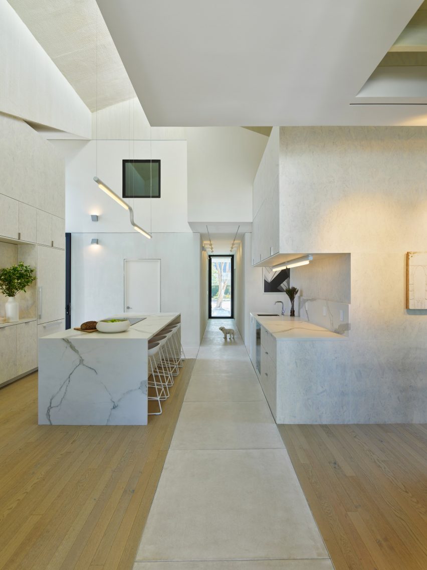 White marble kitchen with wood flooring and a concrete footpath