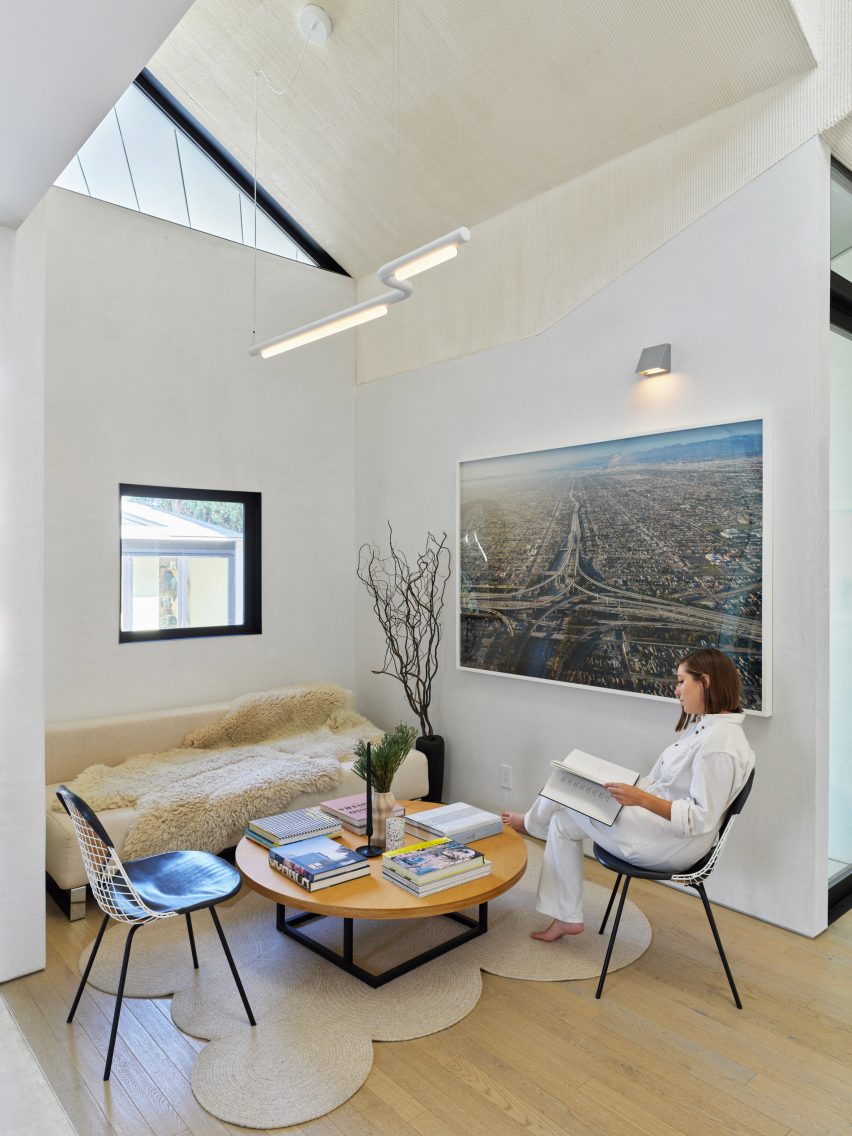 White lounge space with wood flooring, table, chairs and a sofa