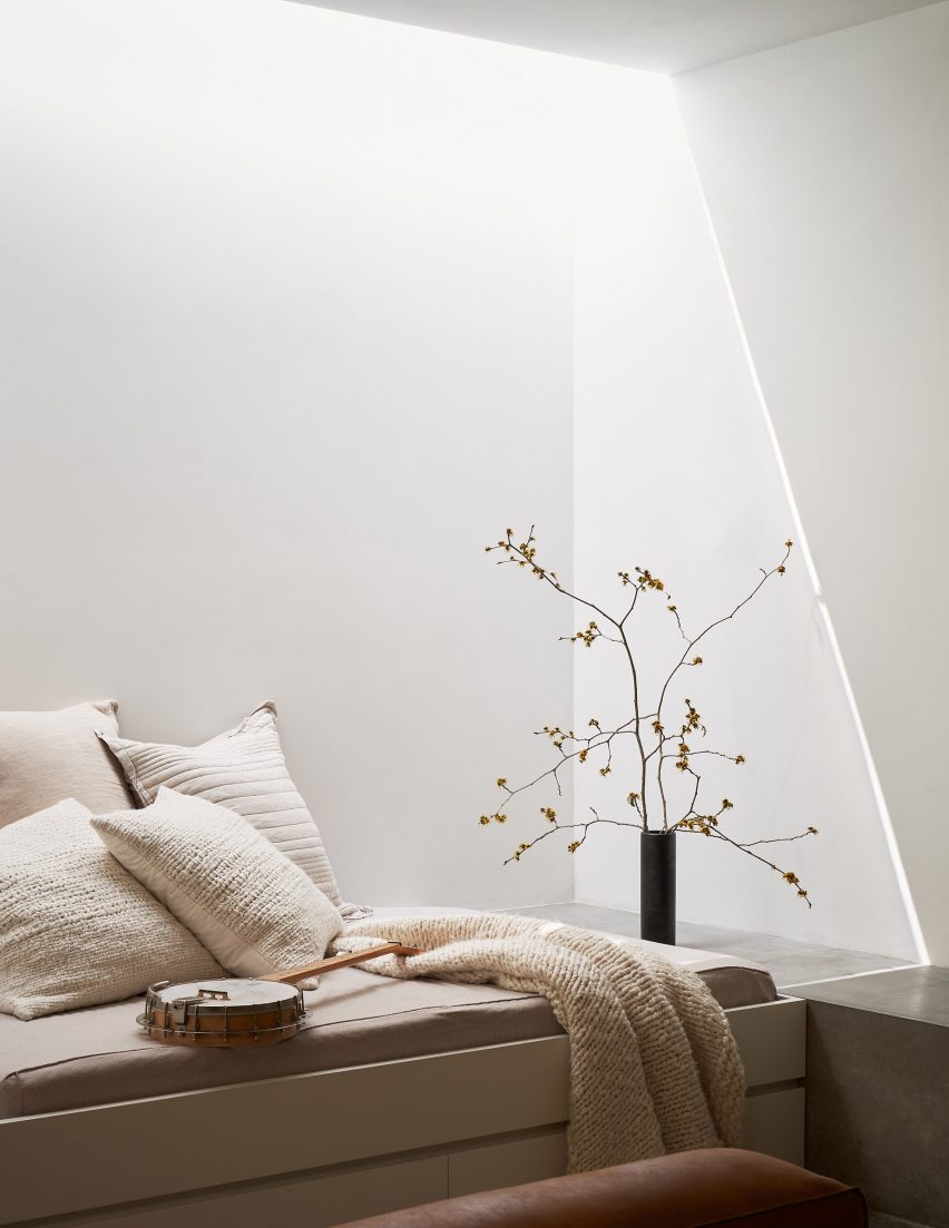 Concrete bench seating in a white room with white cushions and blanket