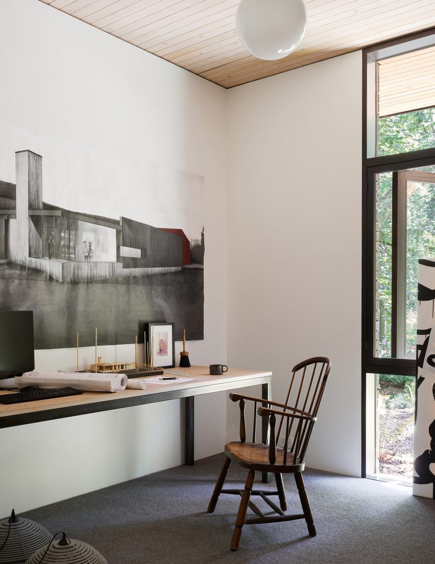 Wooden desk and chair in a white room with concrete floors