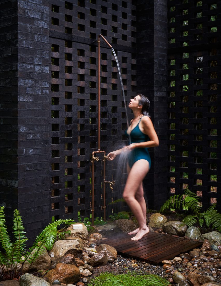 Outdoor shower with a perforated black brick wall