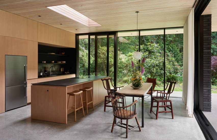 Open-plan kitchen with wooden unit, island and dining table with chairs