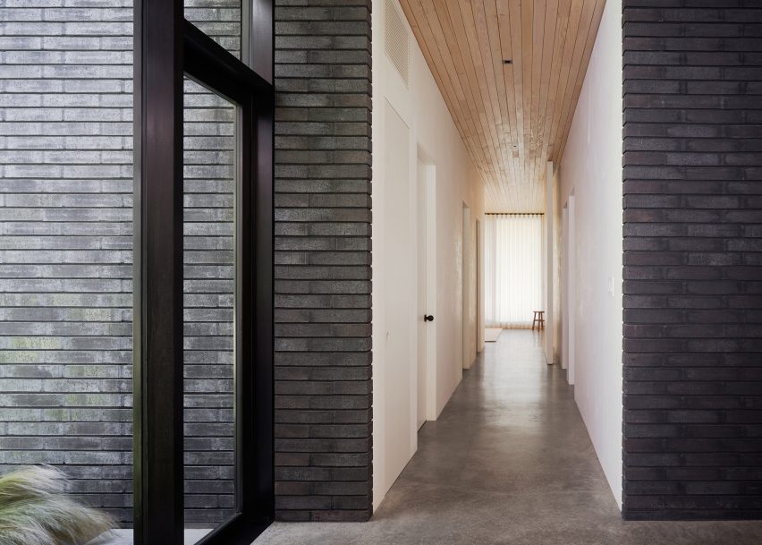 Corridor with white and black brick walls, concrete floors and wood ceiling
