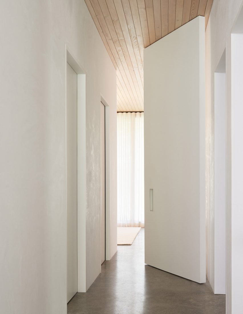 Corridor with white walls, wood ceiling and concrete floor