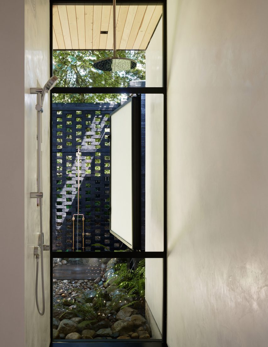 Shower next to a floor-to-ceiling window looking onto an outdoor garden