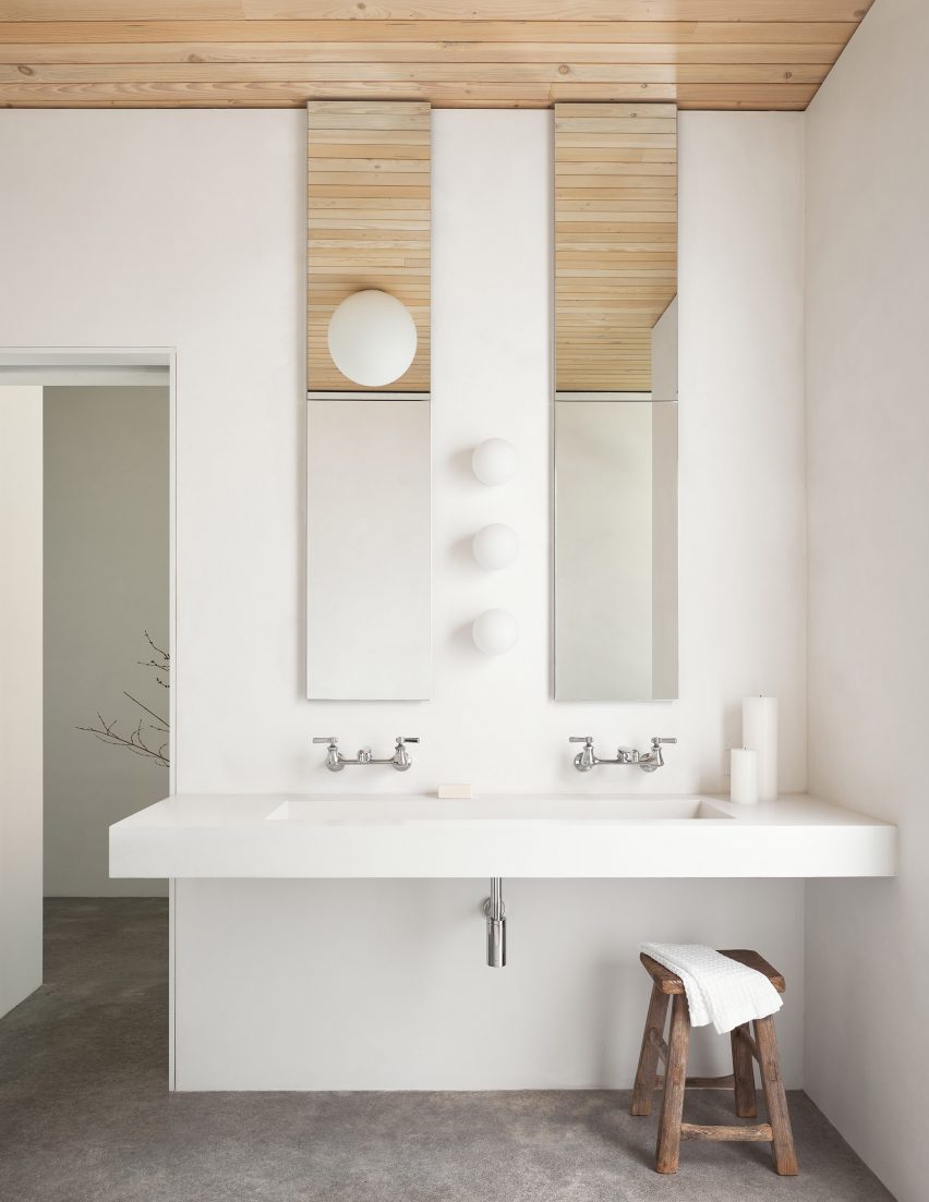 White bathroom with a double sink, timber ceiling and concrete flooring