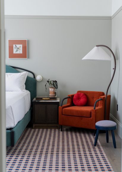 Bedroom with grey walls, checkered carpet and a red accent chair