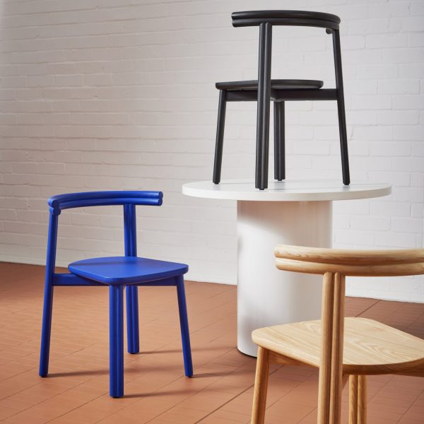 Blue chair beside white table in front of white brick wall