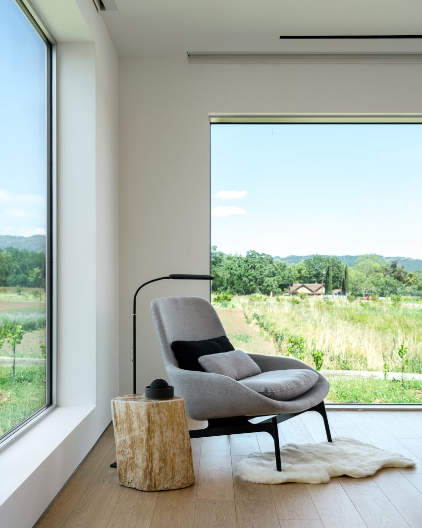 Lounge chair in a room with windows overlooking a field
