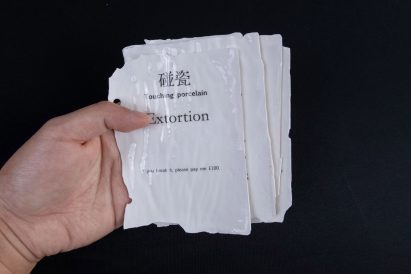 Hand holding white porcelain sheets with text printed across
