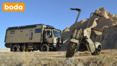 Electric off-road motorcycle in front of a camper van and mountains