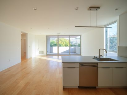 Open-plan kitchen and living room with white walls and wood flooring
