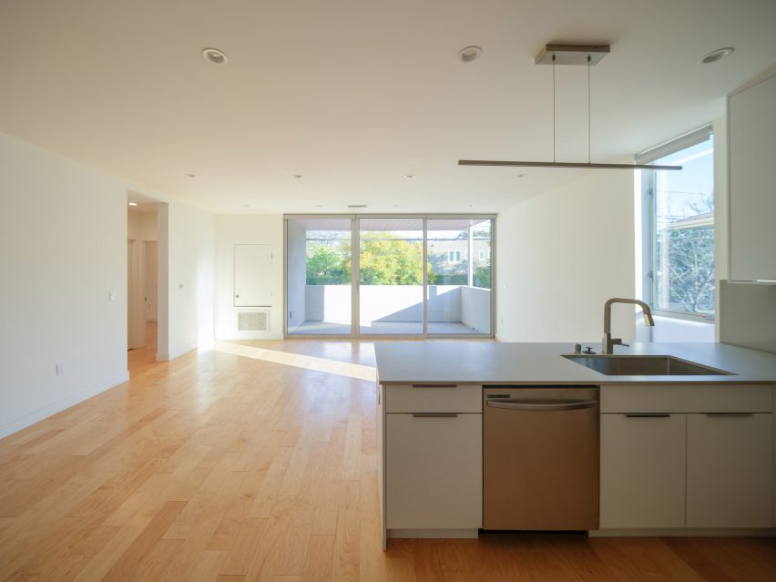 Open-plan kitchen and living room with white walls and wood flooring