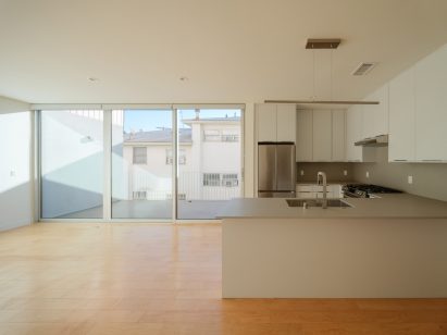 Open-plan kitchen and living room with white walls and wood flooring