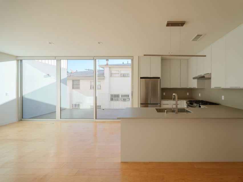 Open-plan kitchen and living room with white walls and wood flooring
