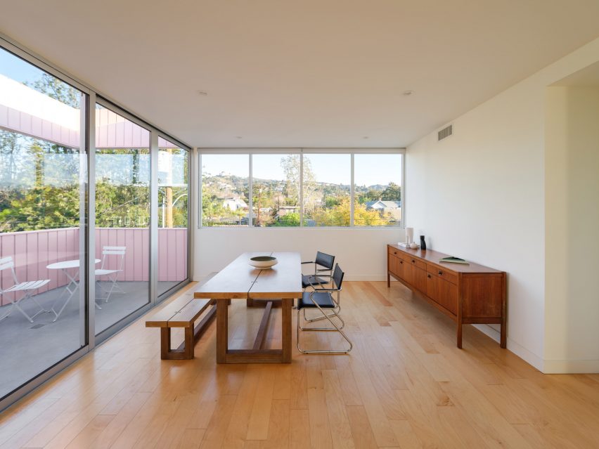 Dining room with wooden floors and sliding glass doors leading to a terrace with pink walls