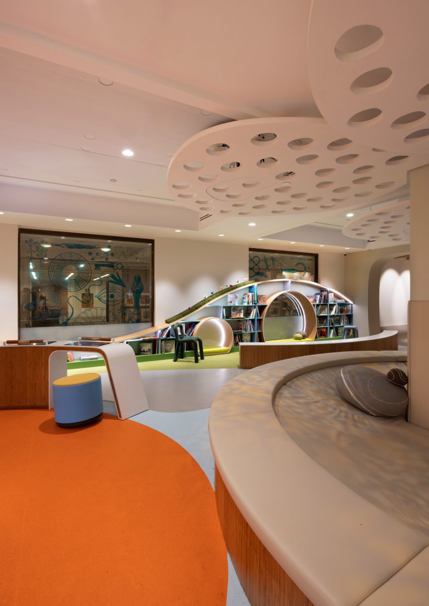 A room with orange floor, sloping shelving, stools and benches