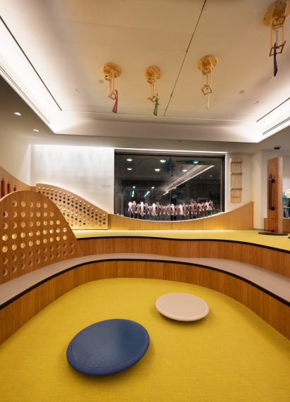 Curved seating around a yellow carpet with balancing furniture