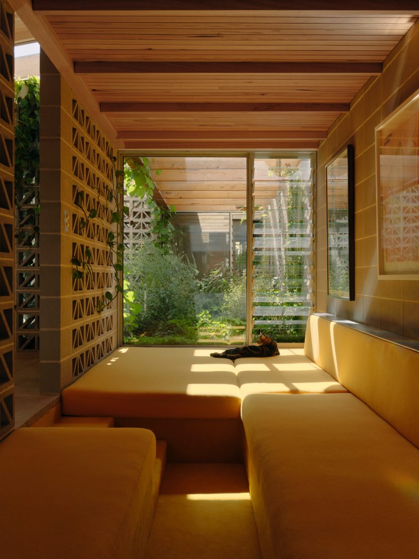 Yellow cushioned window seating nook with perforated breeze block walls by Architecture Architecture