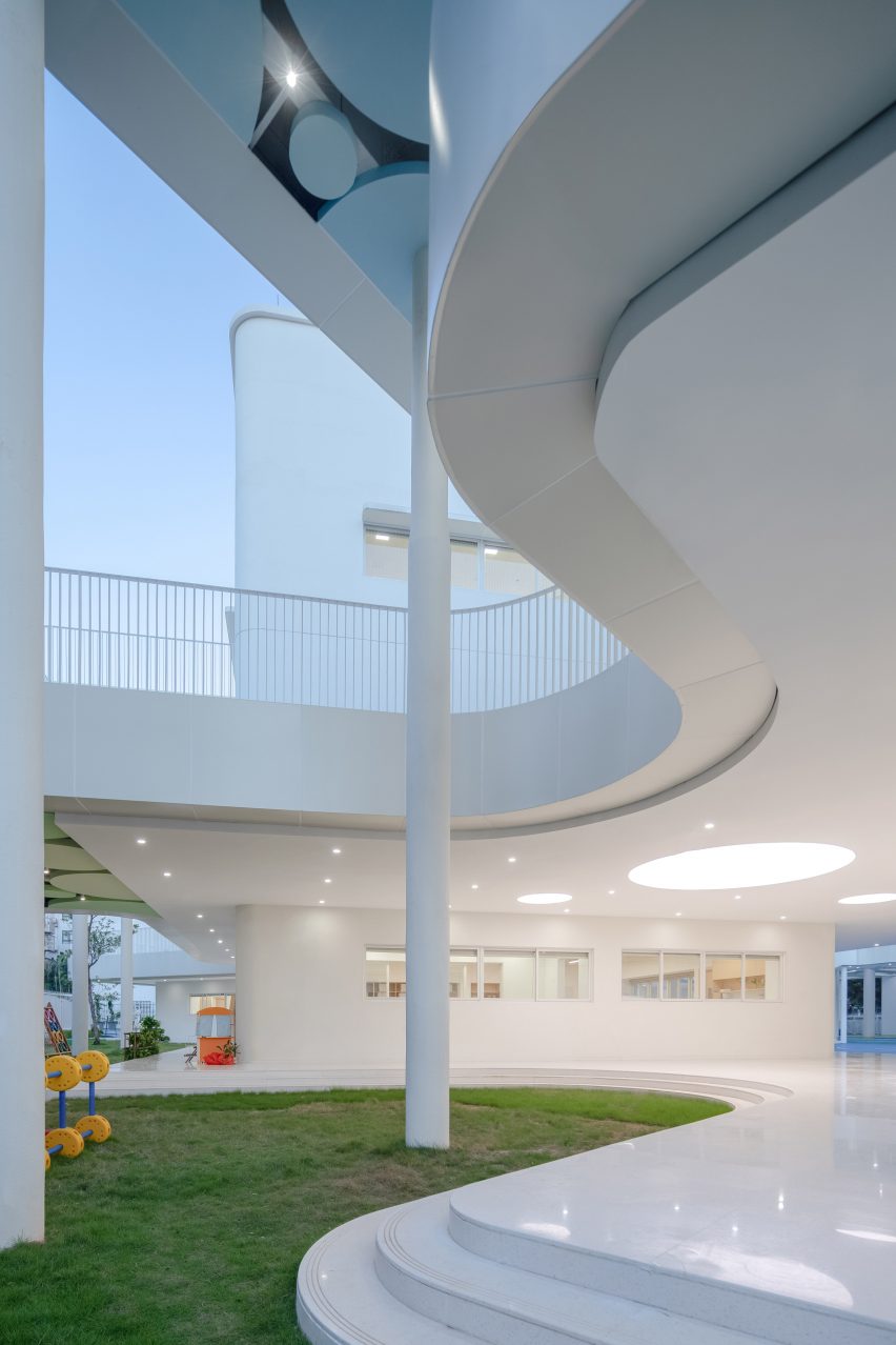 Grassy outdoor space outside the curving Kindergarten of Museum Forest by Atelier Apeiron
