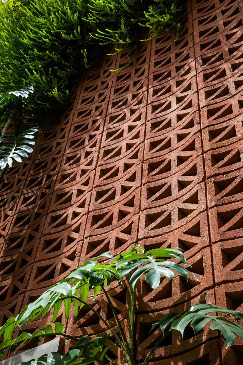 Red perforated cement block facade covered in plants