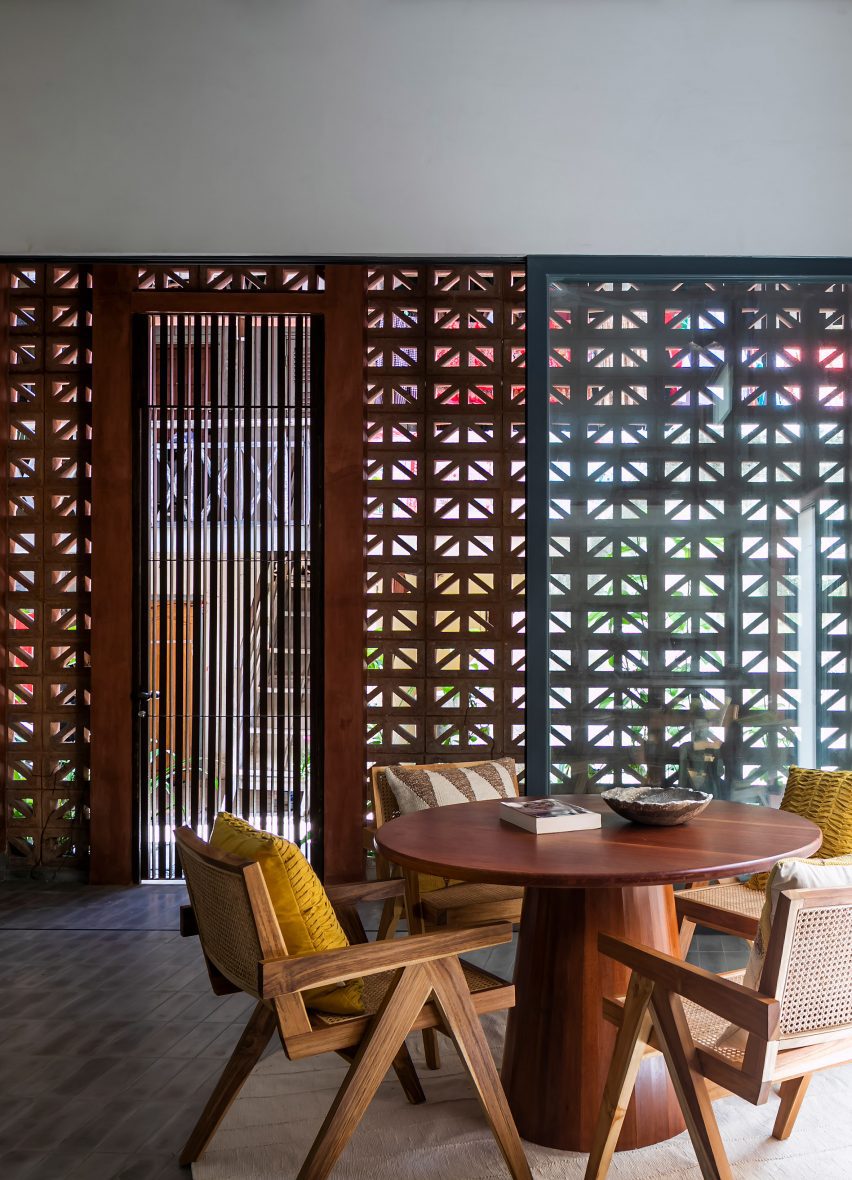 Wooden dining table and chairs in a room with perforated cement block walls