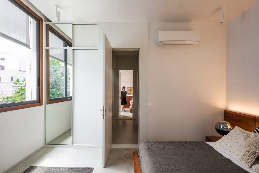 Bedroom with white walls, grey bedding and wood-framed windows
