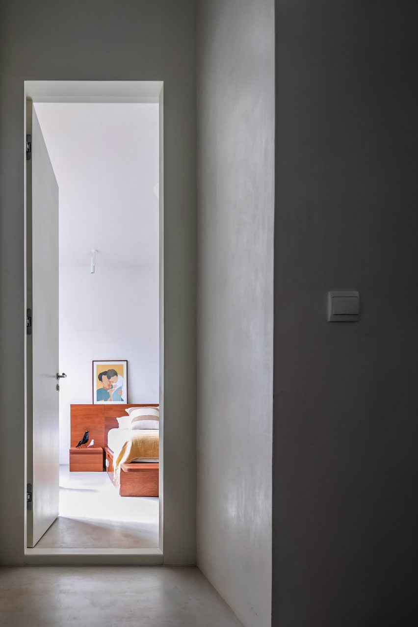 Grey plastered corridor with an open door leading to a bedroom