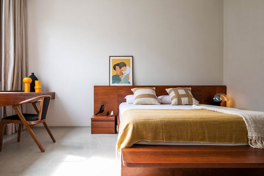 Bedroom with white walls and wooden desk, chair and bed headboard