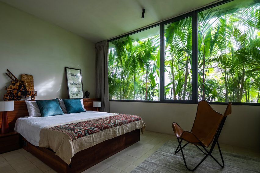 Bedroom with large windows covered by verdant planting