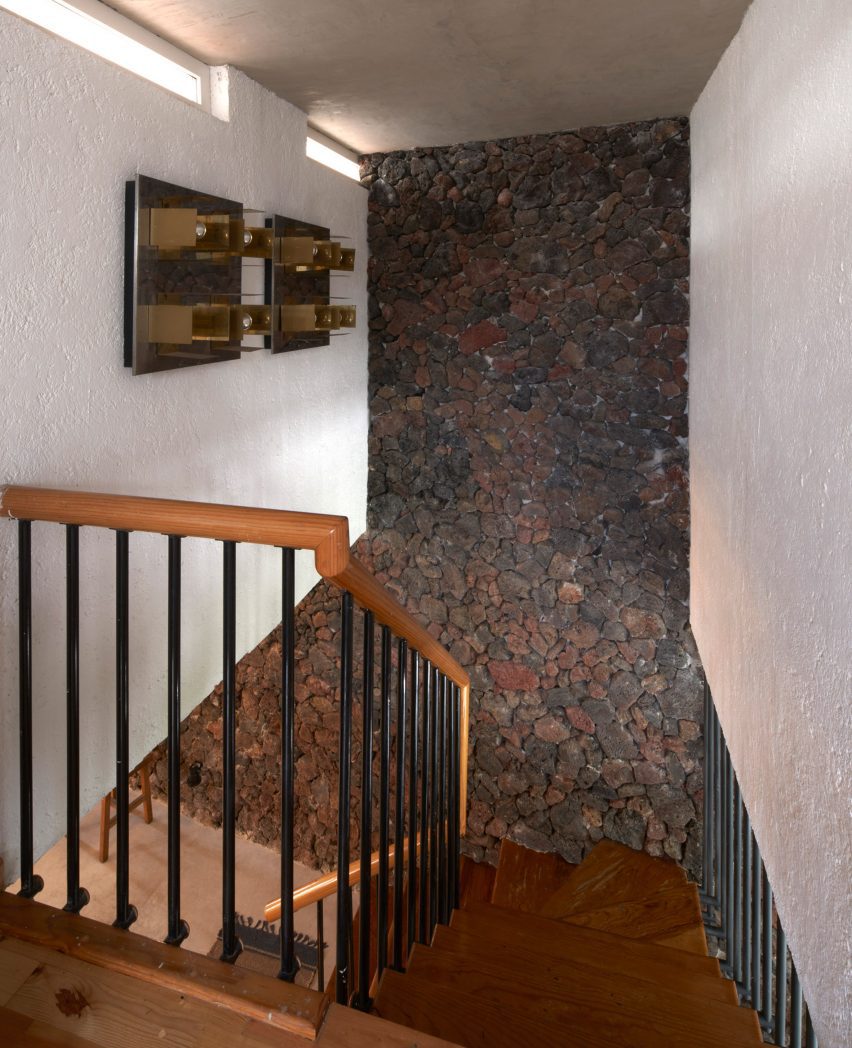 A wooden staircase with a stone wall