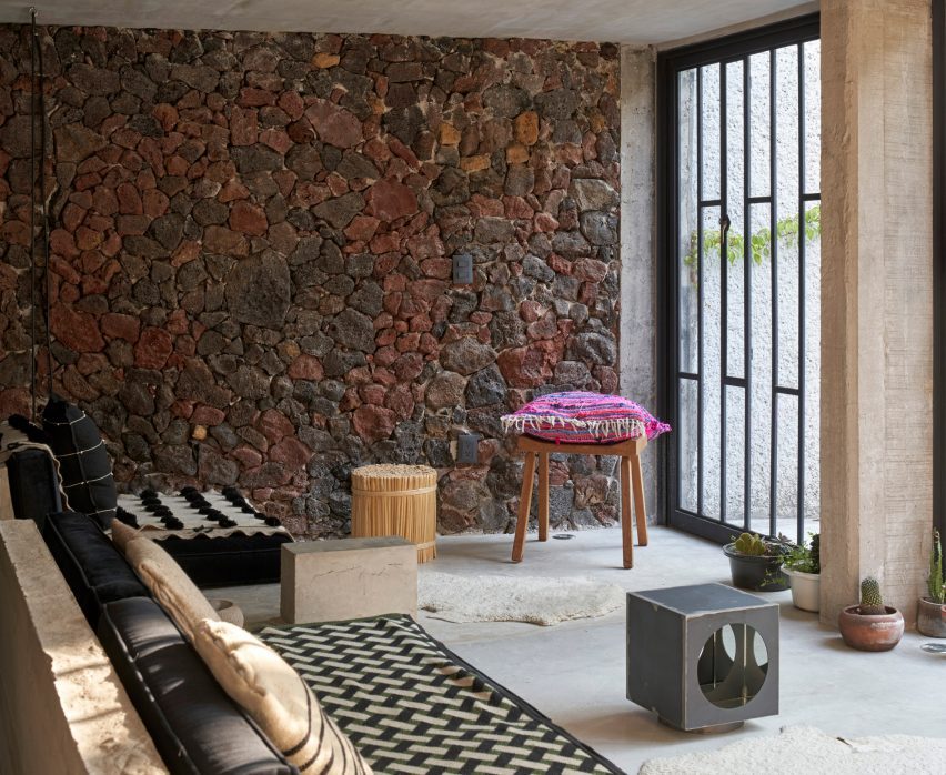 A living room with a dark red and gray stone wall