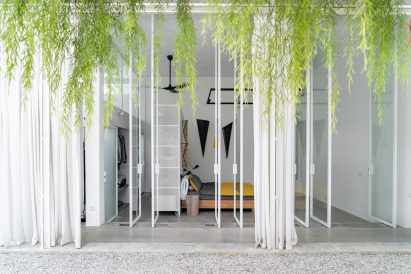 Courtyard with white-framed glass doors opening into a bedroom with hanging plants