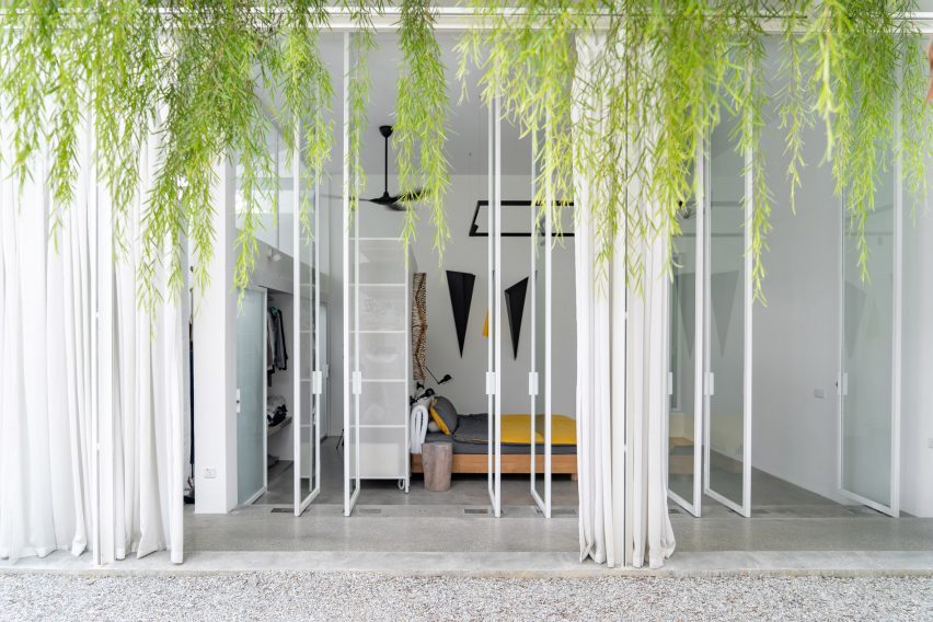 Courtyard with white-framed glass doors opening into a bedroom with hanging plants