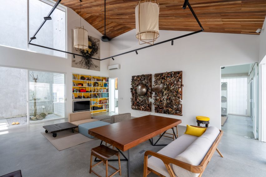 Double-height living space with white walls, concrete flooring and timber ceiling