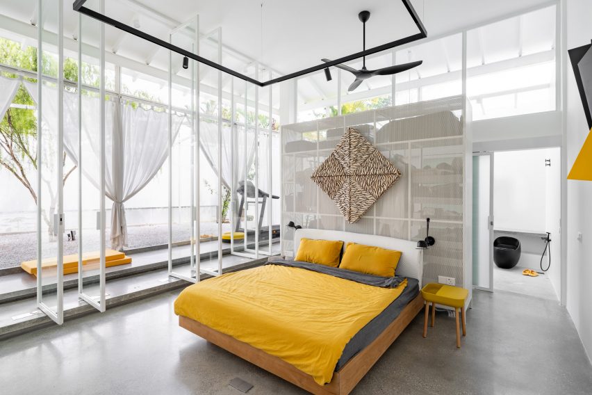 Double-height bedroom with large windows, concrete floor and yellow bedding