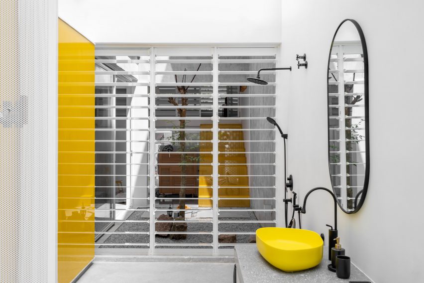 Bathroom with white screen wall and black and yellow sink and taps