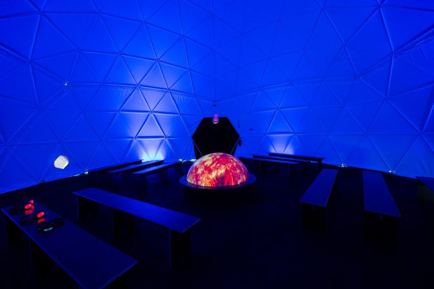 A half-globe shaped installation surrounded by benches