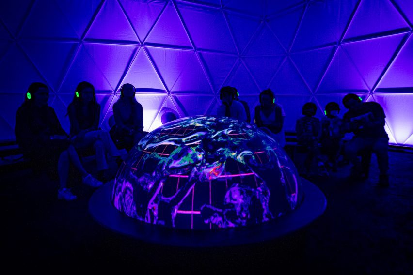 A half-globe shaped installation surrounded by people